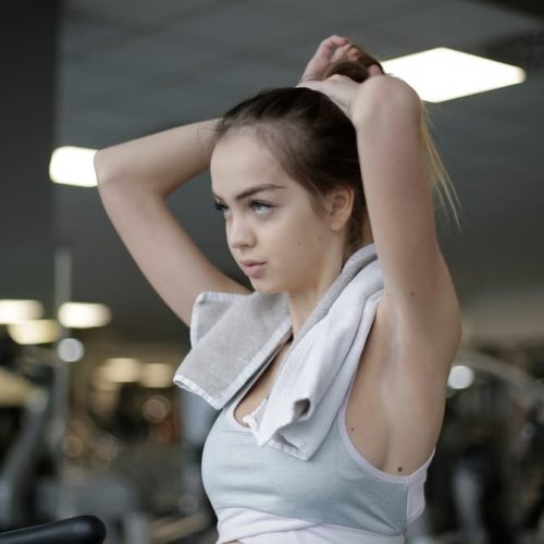 Woman adjusting ponytail in gym, ready to start her fitness routine. Determined and focused.