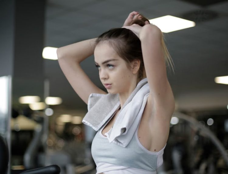 Woman adjusting ponytail in gym, ready to start her fitness routine. Determined and focused.