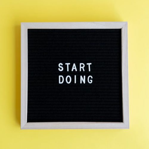 Black message board with 'Start Doing' on a bright yellow background for inspiration.