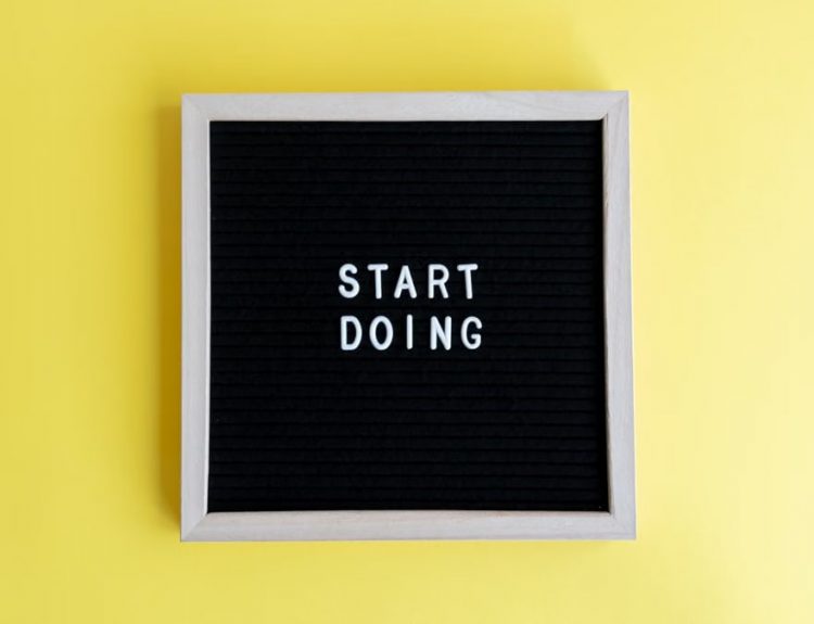 Black message board with 'Start Doing' on a bright yellow background for inspiration.